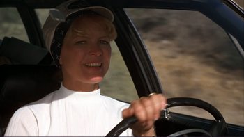 A woman driving a car wearing a white shirt