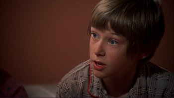 Movie still from “Alice Doesn't Live Here Anymore” (1974), directed by Martin Scorsese – A young boy is sitting down and looking at the camera; Close Up shot, High angle