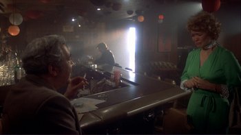Movie still from “Alice Doesn't Live Here Anymore” (1974), directed by Martin Scorsese – A man sitting at a bar drinking a beverage from a cup; Wide shot, Over the shoulder angle