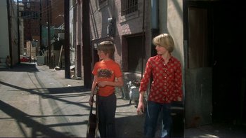 Movie still from “Alice Doesn't Live Here Anymore” (1974), directed by Martin Scorsese – Two young boys walking down the street with a guitar; Wide shot, High angle
