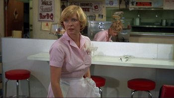 Movie still from “Alice Doesn't Live Here Anymore” (1974), directed by Martin Scorsese – A woman in a pink shirt and apron in a diner; Medium shot, Over the shoulder angle