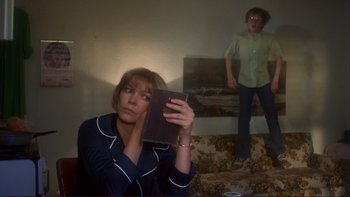Movie still from “Alice Doesn't Live Here Anymore” (1974), directed by Martin Scorsese – A woman holding an open book in front of a man; Medium shot, Low angle