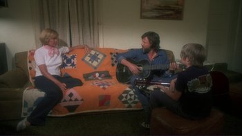 Movie still from “Alice Doesn't Live Here Anymore” (1974), directed by Martin Scorsese – A group of people sitting on top of an orange couch; Wide shot, High angle