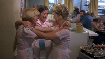 Movie still from “Alice Doesn't Live Here Anymore” (1974), directed by Martin Scorsese – A group of women hugging in front of a group of people; Medium shot, Low angle