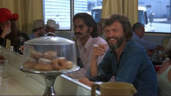 Movie still from “Alice Doesn't Live Here Anymore” (1974), directed by Martin Scorsese – A couple of men sitting at a table with donuts; Medium shot, Over the shoulder angle