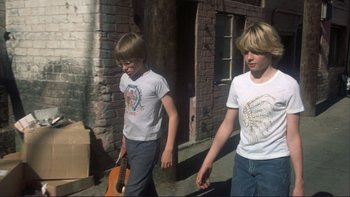 Movie still from “Alice Doesn't Live Here Anymore” (1974), directed by Martin Scorsese – Two young boys walking down the street with a guitar; Medium shot, High angle