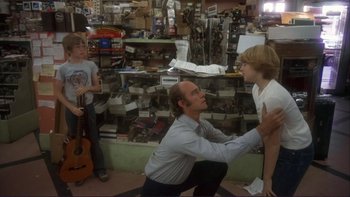 Movie still from “Alice Doesn't Live Here Anymore” (1974), directed by Martin Scorsese – A man kneeling down in front of two boys; Wide shot, Over the shoulder angle