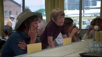 Movie still from “Alice Doesn't Live Here Anymore” (1974), directed by Martin Scorsese – A young boy is looking in the mirror while two other young people look on; Medium shot, Over the shoulder angle