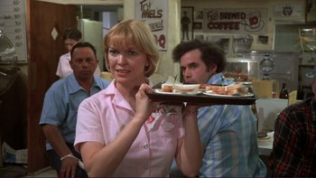 Movie still from “Alice Doesn't Live Here Anymore” (1974), directed by Martin Scorsese – A woman holding a tray of food in a restaurant; Medium shot, Over the shoulder angle