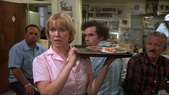 Movie still from “Alice Doesn't Live Here Anymore” (1974), directed by Martin Scorsese – A woman holding a tray with food on top of it; Medium shot, Over the shoulder angle