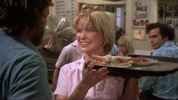 Movie still from “Alice Doesn't Live Here Anymore” (1974), directed by Martin Scorsese – A woman holding a tray of food at a restaurant; Medium shot, Over the shoulder angle