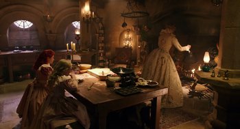 Movie still from “Alice Through the Looking Glass” (2016), directed by James Bobin – A woman in an old fashioned dress standing in front of a table; Wide shot, Over the shoulder angle