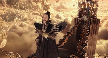 Movie still from “Alice Through the Looking Glass” (2016), directed by James Bobin – A man with a beard is standing in a castle; Wide shot, High angle