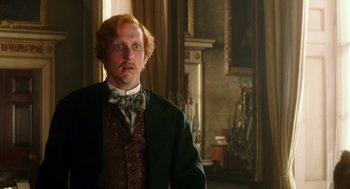 Movie still from “Alice Through the Looking Glass” (2016), directed by James Bobin – A man with a red beard wearing a suit and tie; Medium shot, Low angle