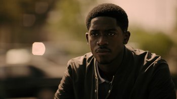 Movie still from “Snowfall” (2017), directed by Hiro Murai – A person wearing a jacket with trees in the background; Close Up shot, Over the shoulder angle