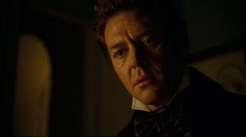 Movie still from “Alice in Wonderland” (2010), directed by Tim Burton – A person wearing a bow tie; Close Up shot, Over the shoulder angle