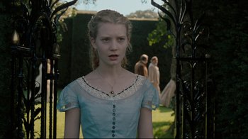 Movie still from “Alice in Wonderland” (2010), directed by Tim Burton – A woman in a blue dress standing next to a tree; Medium shot, Over the shoulder angle