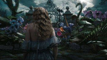 Movie still from “Alice in Wonderland” (2010), directed by Tim Burton – A woman standing in front of a lush garden; Wide shot, High angle