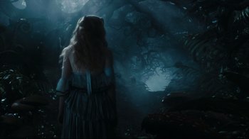 Movie still from “Alice in Wonderland” (2010), directed by Tim Burton – A woman standing in the middle of a dark forest; Wide shot, Over the shoulder angle