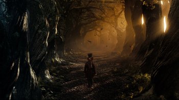 Movie still from “Alice in Wonderland” (2010), directed by Tim Burton – A man walking through a dark forest at night; Extreme Wide shot, High angle