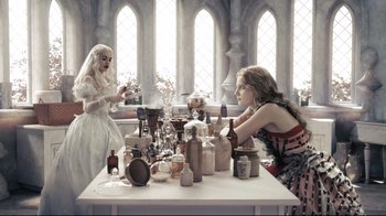 Movie still from “Alice in Wonderland” (2010), directed by Tim Burton – Two women sitting at a table with bottles and vases on top of it; Medium shot, High angle