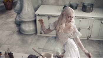 Movie still from “Alice in Wonderland” (2010), directed by Tim Burton – A woman dressed as a white witch cooking in a kitchen; Medium shot, High angle