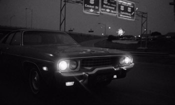 Movie still from “Alice in the Cities” (1974), directed by Wim Wenders – A black and white photo of a car on the road at night; Wide shot, Low angle