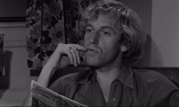 Movie still from “Alice in the Cities” (1974), directed by Wim Wenders – Black and white photograph of a man reading a book; Close Up shot, Low angle
