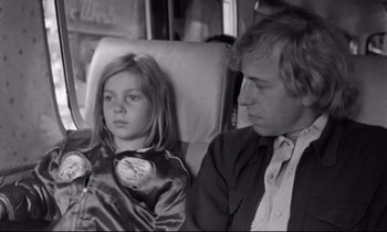 Movie still from “Alice in the Cities” (1974), directed by Wim Wenders – A man and a little girl sitting next to each other; Close Up shot, Over the shoulder angle