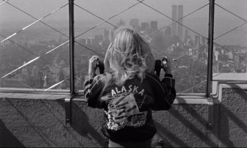 Movie still from “Alice in the Cities” (1974), directed by Wim Wenders – A woman taking a picture of a city from the top of a skyscraper; Close Up shot, Overhead angle