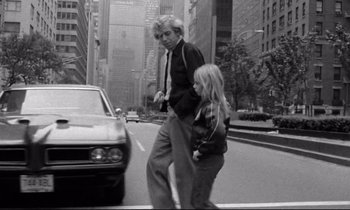 Movie still from “Alice in the Cities” (1974), directed by Wim Wenders – A man and a woman crossing a street in a city; Medium shot, Low angle