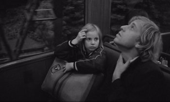 Movie still from “Alice in the Cities” (1974), directed by Wim Wenders – A young girl sitting next to an adult on a bus; Close Up shot, High angle