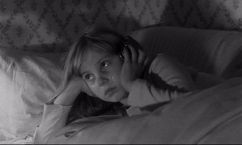 Movie still from “Alice in the Cities” (1974), directed by Wim Wenders – A young girl laying in a bed with a cell phone to her ear; Close Up shot, High angle