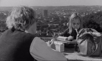 Movie still from “Alice in the Cities” (1974), directed by Wim Wenders – Two women sitting at a table with a city view in the background; Medium shot, High angle
