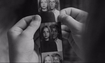 Movie still from “Alice in the Cities” (1974), directed by Wim Wenders – A person holding a photo strip of a man and a woman; Extreme Close Up shot, High angle