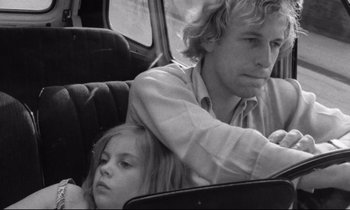 Movie still from “Alice in the Cities” (1974), directed by Wim Wenders – A man and a young girl sitting in the back seat of a car; Close Up shot, Low angle