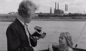 Movie still from “Alice in the Cities” (1974), directed by Wim Wenders – A man and a girl in a boat on a river; Medium shot, Over the shoulder angle