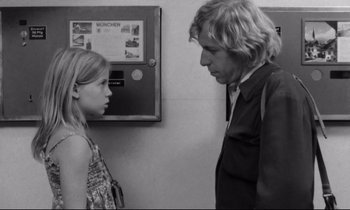 Movie still from “Alice in the Cities” (1974), directed by Wim Wenders – A man and a little girl standing next to each other; Medium shot, Over the shoulder angle