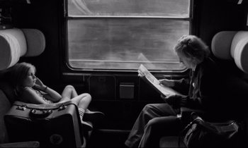 Movie still from “Alice in the Cities” (1974), directed by Wim Wenders – Two women are sitting on a train reading a magazine; Medium shot, Over the shoulder angle