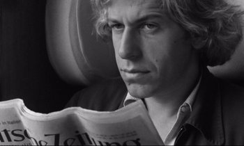 Movie still from “Alice in the Cities” (1974), directed by Wim Wenders – A man reading a newspaper while sitting in a car; Close Up shot, Low angle