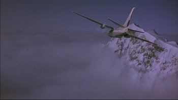 Movie still from “Alive” (1993), directed by Frank Marshall – An airplane is flying over the clouds in the sky; Extreme Wide shot, Low angle