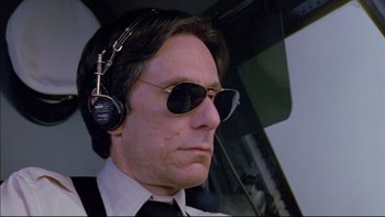 Movie still from “Alive” (1993), directed by Frank Marshall – A man wearing sunglasses and a tie with headphones on his head; Close Up shot, Low angle