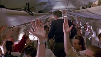 Movie still from “Alive” (1993), directed by Frank Marshall – A group of people on a plane with their hands up; Wide shot, High angle
