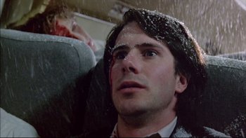 Movie still from “Alive” (1993), directed by Frank Marshall – A man with long black hair is sitting in the rain; Close Up shot, Overhead angle