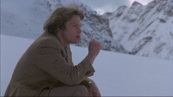 Movie still from “Alive” (1993), directed by Frank Marshall – A man sitting in the snow holding a cigarette in his mouth; Medium shot, Low angle