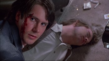 Movie still from “Alive” (1993), directed by Frank Marshall – A man with a knife in his face and a woman with a knife in her hand laying on the ground; Close Up shot, Over the shoulder angle