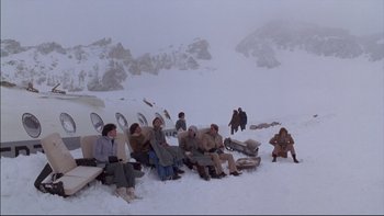 Movie still from “Alive” (1993), directed by Frank Marshall – A group of people sitting on top of a snow covered slope; Wide shot, High angle