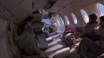 Movie still from “Alive” (1993), directed by Frank Marshall – An interior of an airplane that has a lot of stuff on the floor; Wide shot, Overhead angle