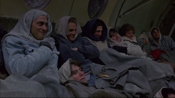 Movie still from “Alive” (1993), directed by Frank Marshall – A group of people sitting on a plane with blankets on them; Wide shot, High angle