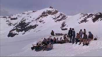 Movie still from “Alive” (1993), directed by Frank Marshall – A group of people sitting on top of a snow covered slope; Extreme Wide shot, High angle